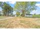Backyard with a mix of tall pines and large trees, featuring a garage and a carport at 8917 Fowler Rd, Zebulon, NC 27597