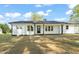 Front view of a beautiful white home featuring a modern front door and manicured lawn at 8917 Fowler Rd, Zebulon, NC 27597