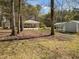 Backyard with mature trees, an outbuilding, and partial view of the house at 906 Perry Rd, Zebulon, NC 27597