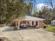 Brick ranch-style home with covered parking area, mature trees and a long driveway at 906 Perry Rd, Zebulon, NC 27597