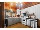 A traditional kitchen featuring wood paneled walls and ceiling, a window with patterned curtains, and updated appliances at 906 Perry Rd, Zebulon, NC 27597