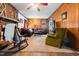 Cozy living room with a fireplace, comfortable sofas, rocking chair, and wood paneled walls at 906 Perry Rd, Zebulon, NC 27597