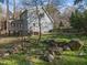 Green backyard with a two-story home, porch and natural stone landscaping at 109 Boulder Ln, Chapel Hill, NC 27514