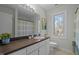 Bright bathroom features a brown countertop, cream cabinets, a large mirror, and a serene window view at 109 Boulder Ln, Chapel Hill, NC 27514
