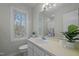 Bathroom with a cream-colored vanity, toilet, large mirror, and a bright window overlooking wooded scenery at 109 Boulder Ln, Chapel Hill, NC 27514