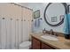 Bathroom with blue walls featuring a dark wood vanity and circular mirror at 120 Teasel Ct, Clayton, NC 27527