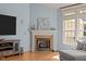 Living room showcasing a fireplace with mantle, a large window, and hardwood floors at 120 Teasel Ct, Clayton, NC 27527