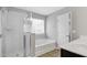 Bright bathroom featuring a glass shower, soaking tub beneath a window, and a vanity with dual sinks at 127 S Harrison Place Ln, Fuquay Varina, NC 27526