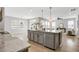 View of kitchen island with stainless dishwasher and view of the open-concept living area with hardwood flooring at 127 S Harrison Place Ln, Fuquay Varina, NC 27526