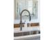 Close-up of a sleek stainless steel kitchen sink with a modern faucet and a decorative artwork in the background at 1317 Garner Rd # 101, Raleigh, NC 27610