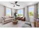 Sunlit living room with ample seating, including leather chairs, and a view through expansive windows at 1317 Garner Rd # 101, Raleigh, NC 27610