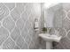 Stylish powder room with patterned wallpaper, a pedestal sink, a decorative mirror, and a neutral color scheme at 1317 Garner Rd # 101, Raleigh, NC 27610
