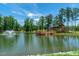 Scenic view of the pond with a fountain, pier, and a beautiful log cabin in the background, perfect for nature lovers at 1905 Cedar Dam Ln, Wendell, NC 27591