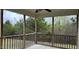 Relaxing covered back porch with a wood railing and scenic views of the surrounding trees at 194 Cornfield Ln, Benson, NC 27504