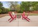 This outdoor space features a backyard fire pit surrounded by red and white Adirondack chairs at 2001 Lilly Brook St, Fuquay Varina, NC 27526