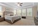 Bright main bedroom featuring tray ceilings, a ceiling fan, and three large windows for ample natural light at 2421 Trenton Park Ln, Raleigh, NC 27607