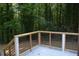 A view of a new deck with natural wood railings and black spindles overlooking a tranquil and lush green forest at 245 Marilyn Cir, Cary, NC 27513