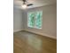 Bedroom with hardwood floors, ceiling fan, and large window offering wooded views at 245 Marilyn Cir, Cary, NC 27513