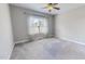 Simple carpeted bedroom featuring a large window, ceiling fan, and light gray walls at 2540 Levi Ln, Bahama, NC 27503