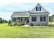 Charming grey home with light grey trim and blue shutters surrounded by a lush green lawn and mature landscaping at 2540 Levi Ln, Bahama, NC 27503