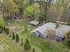 Aerial view showing the home's backyard with an outdoor kitchen, fire pit, garden, garage, and spacious lawn at 2920 Ode Turner Rd, Hillsborough, NC 27278