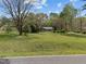 Property with a large, green front lawn, mature trees, and a glimpse of the house's exterior at 2920 Ode Turner Rd, Hillsborough, NC 27278