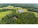 Aerial view of estate featuring a pond, pastures, farmland, barn and a home nestled in the trees at 301 Stone Currie Dr, Hillsborough, NC 27278