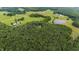 Aerial view of property showing meadows, farm and house nestled amongst mature trees at 301 Stone Currie Dr, Hillsborough, NC 27278