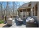 Relax on this outdoor deck with wicker furniture, a striped rug, and a serene view of the surrounding woods at 301 Stone Currie Dr, Hillsborough, NC 27278