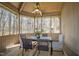 This well-lit porch features a dining table and fan, offering an inviting space with views of the trees and sunshine at 301 Stone Currie Dr, Hillsborough, NC 27278