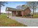 Brick home featuring a covered area, gravel driveway, and manicured landscaping at 3026 Shoeheel Rd, Kenly, NC 27542