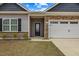 Charming home exterior showcasing a mix of stone, gray siding, and a two-car garage, set under a bright blue sky at 303 Azalea Gaze Dr, Youngsville, NC 27596