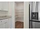 Walk-in pantry includes white shelving, hardwood floors, and stainless refrigerator with water dispenser at 303 Azalea Gaze Dr, Youngsville, NC 27596