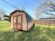 Gable roof barn-style storage shed painted in tan and brown wood trim with double doors in a grassy backyard at 310 Meadowbrook Dr, Burlington, NC 27215