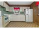 The kitchen featuring wood paneling walls, white cabinets and appliances, with window at 3416 North Ridge Dr, Sanford, NC 27330
