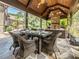Covered outdoor dining area with a stone fireplace and elegant furniture creating a cozy ambiance at 3505 Jonaway Cir, Fuquay Varina, NC 27526