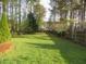 Large green backyard with a wooden fence and mature trees around the perimeter at 3537 Layton Ridge Dr, Apex, NC 27539