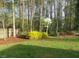 View of serene backyard with green lawn, shrubs, mulch and a perimeter of woods at 3537 Layton Ridge Dr, Apex, NC 27539