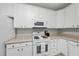 Well-lit kitchen with white cabinets, countertops, and appliances, offering ample space at 408 Indian Elm Ln, Cary, NC 27519