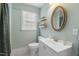 Modern bathroom with a toilet, sink, floating shelves, and an oval mirror at 410 N Hyde Park Ave, Durham, NC 27703