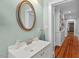 Charming bathroom features a decorative mirror, white vanity, and hardwood floors that extend into the hallway at 410 N Hyde Park Ave, Durham, NC 27703