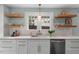 Bright kitchen featuring white cabinets, subway tile backsplash, floating shelves, and stainless dishwasher at 410 N Hyde Park Ave, Durham, NC 27703