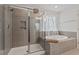 Modern bathroom with a soaking tub, a walk-in shower, and neutral tiling at 433 Mockingbird Ln, Mebane, NC 27302