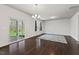 Bright dining room with dark wood floors, modern chandelier, and access to the screened porch at 433 Mockingbird Ln, Mebane, NC 27302