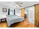 Bright bedroom featuring a barn door, ceiling fan, and hardwood floors with ensuite bath access at 440 S Church St, Coats, NC 27521