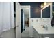 Blue bathroom with white wainscoting, modern fixtures, and a peek into the Primary bedroom at 5520 Mccormick Rd, Durham, NC 27713