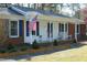 Close up view of the exterior elevation of the charming home, featuring an american flag and a bench at 5520 Mccormick Rd, Durham, NC 27713