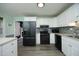 Kitchen features stainless steel appliances, white cabinets, and wood grain flooring at 5520 Mccormick Rd, Durham, NC 27713