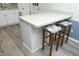 Kitchen island with floral padded stools, white cabinets, and wood grain flooring at 5520 Mccormick Rd, Durham, NC 27713