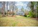 Serene view of a gray house surrounded by mature trees, showcasing the property's peaceful setting at 5608 Ventura Dr, Durham, NC 27712